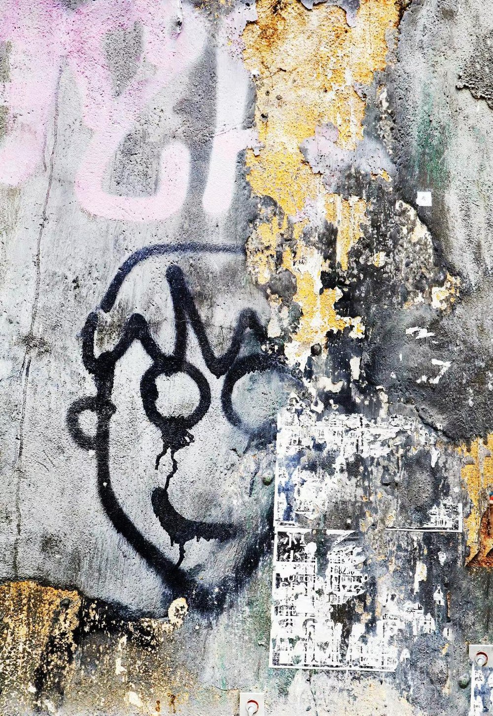 Abstract painting of a graffiti face on a weathered wall with peeling paint